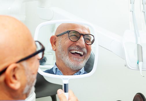Man in glasses smiling in reflection in treatment chair