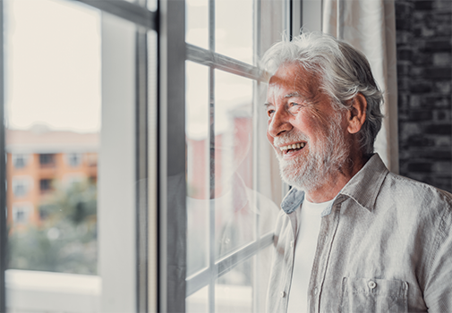 Smiling senior man looking out a window