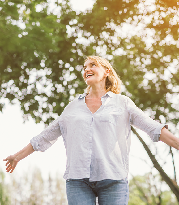 Woman walking outdoors and grinning with All on X dental implants in Medford