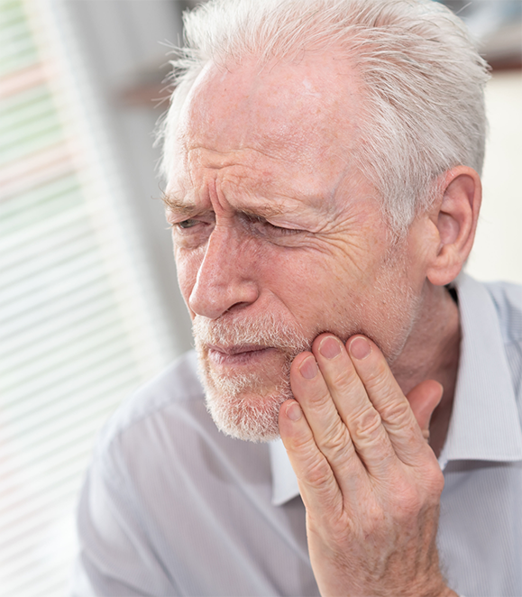 Man holding his cheek in pain before seeing an emergency dentist in Medford