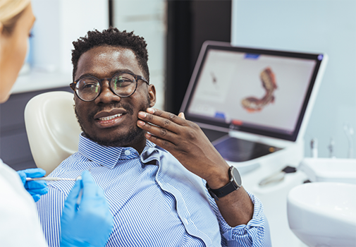 Man holding his cheek while talking to an emergency dentist