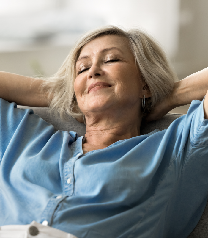 Smiling woman relaxing with her eyes closed and her hands behind her head